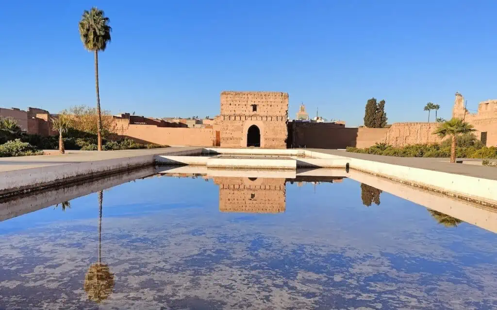 A view of the reflecting pool ana a gate on the palace with one palm tree on the left. This is one of the coolest things to do in Marrakech.