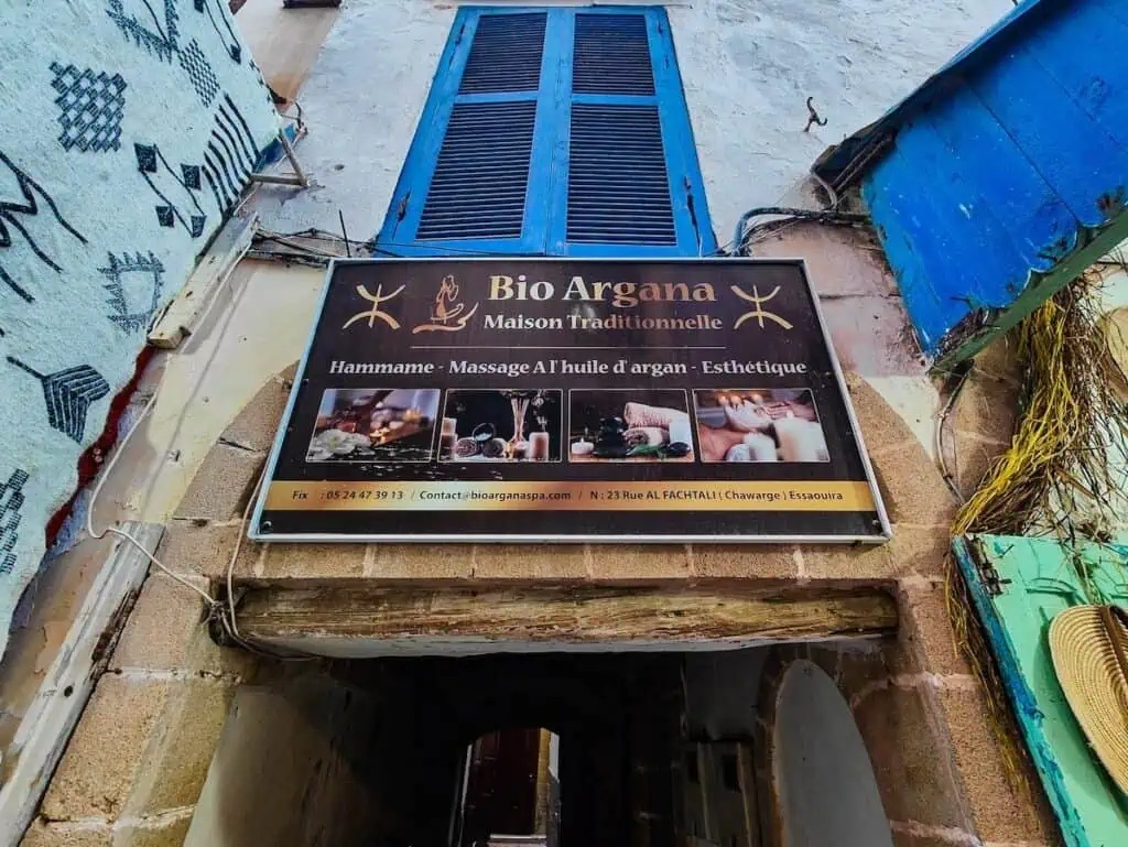 Brown sign for io Argana Hammam with a blue shutter above the sign.