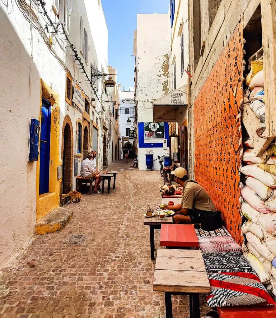 One of the best cafes in Essaouira is located on a small side street in Essaouira. Small tables sit along the street and are lined with cushions.