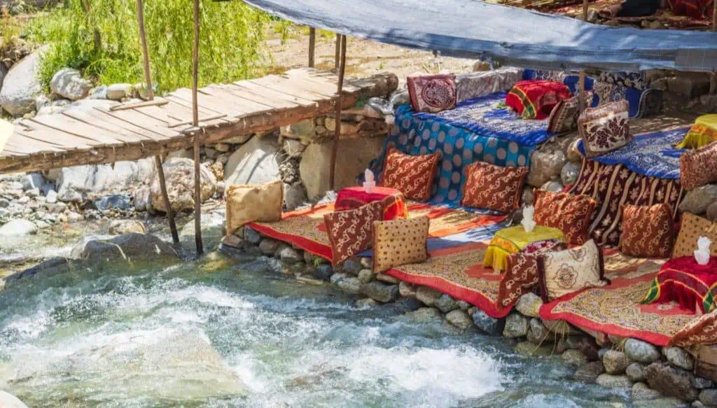 A view of colorful pillows and tables along a river in the Ourika Valley. This is one of the best Atlas Mountains tours from Marrakech.