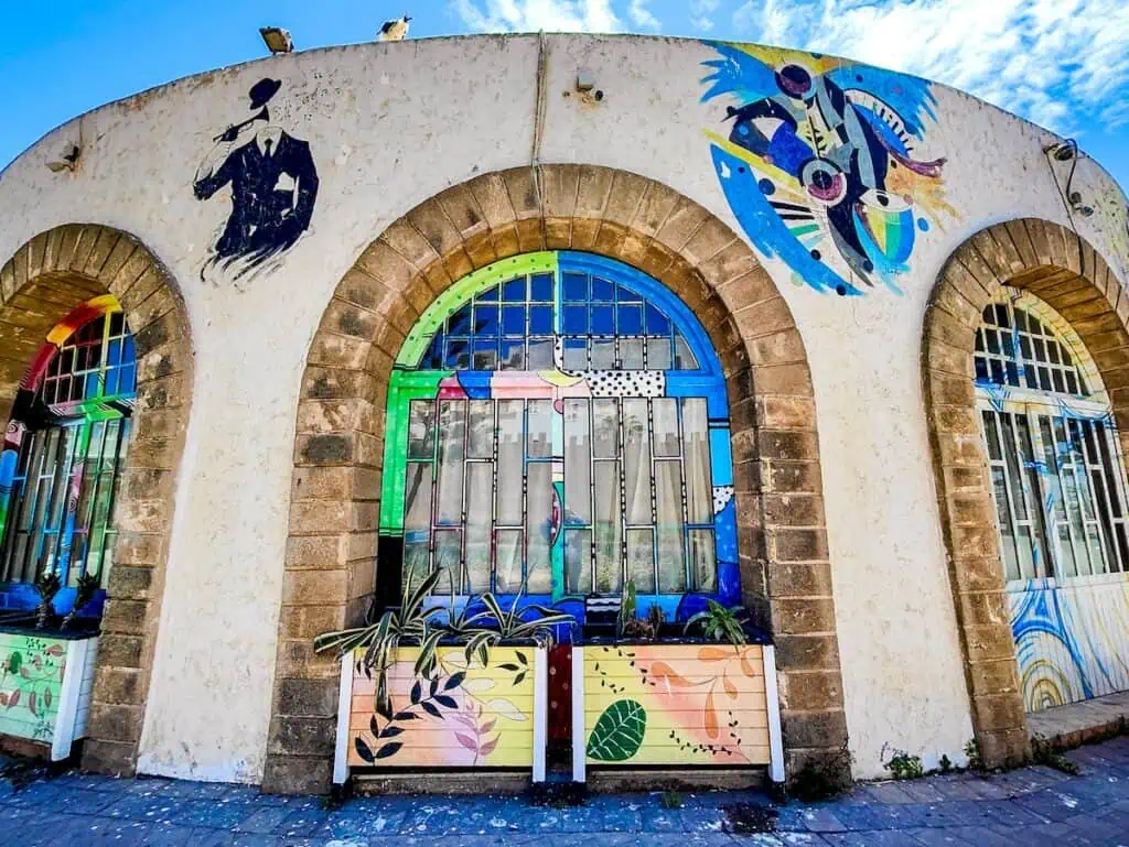 View of the white exterior of D'Jazy restaurant with arched, stone windows and musicians on the exterior.