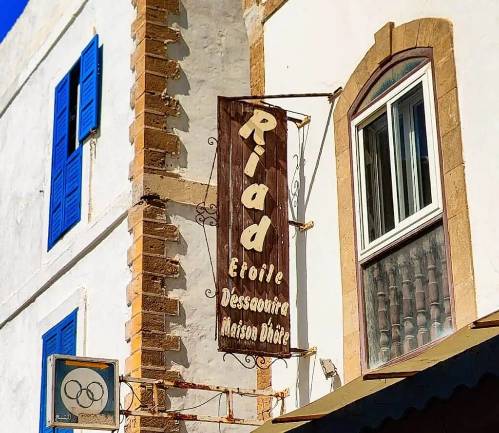 A view of a vertical brown sign in the Medina that says, "Riad E'toile".