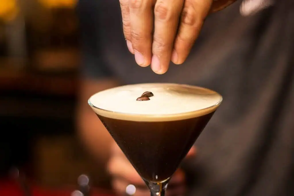 A view of a hand placing coffee beans on top of an espresso martini at one of the coolest bars in Marrakech.