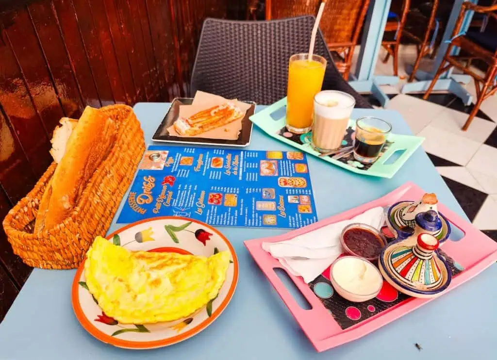 An aerial view of the breakfast on the table at Patisserie Driss with a blue menu and an omelet.