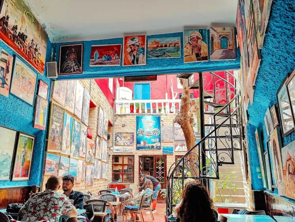 A view of the vibrant blue interior of Patisserie Driss with colorful paintings on the walls and an open courtyard.