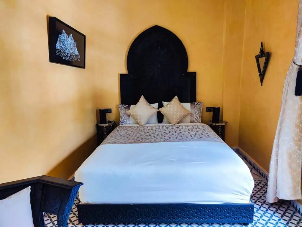 View of a large bed with a yellow wall in the background.