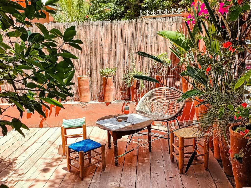 A view of the garden at Some Concept Coffee Shop. You see a table on a patio with chairs and tables surrounded by potted plants and vases at one of the best vegan restaurants Marrakech has to offer.