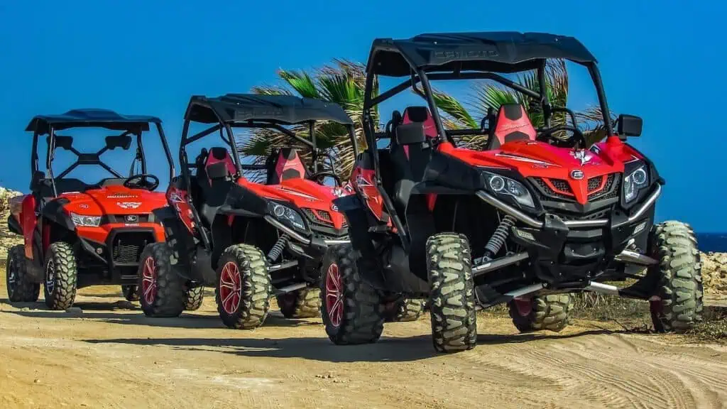 A view of three red dune buggies istting in a row on a road on a sunny day in the sand. Try this after doing some of the best quad biking in Essaouira.
