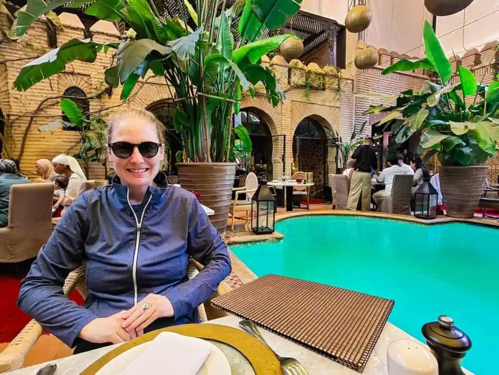 Is morocco safe for women? This photo shows it is. I am sitting in a blue long sleeve zip up shirt in front of a pool at La Trattoira.