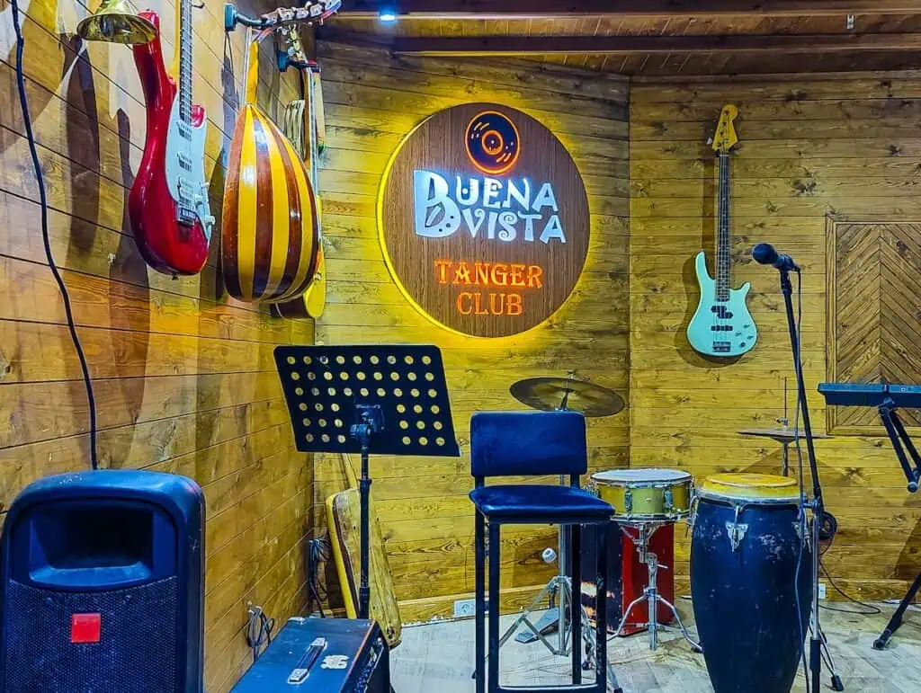 View of the stage at the Buena Vista Club in Tanger and you can see lots of guiters hanging on the walls and a logo for the Buena Vista Club.