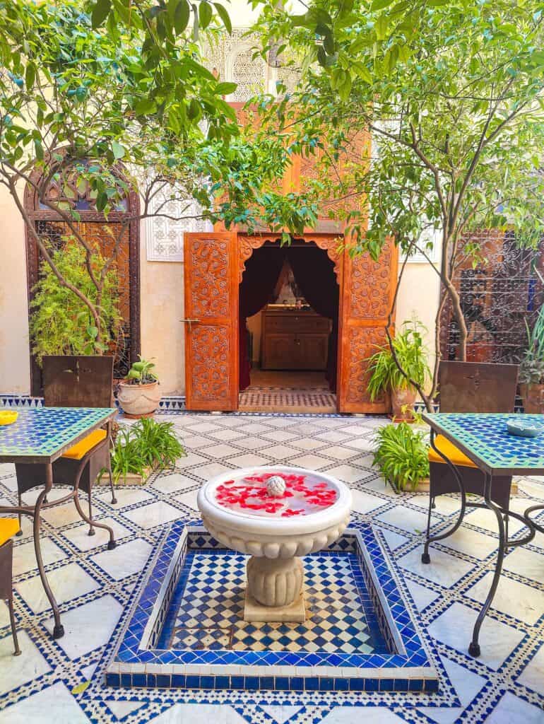 View of the outdoor courtyard inside the perfume museum. You can see tables, a quiet fountain, and wood frames around a door.