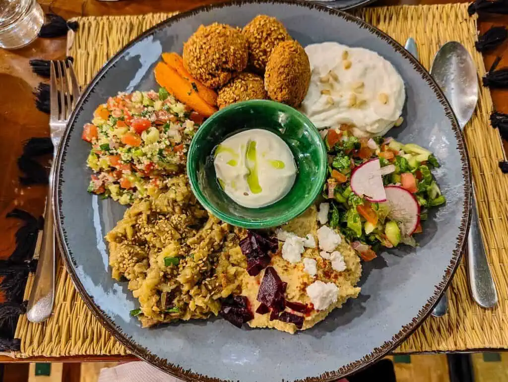 Aerial view of my mezze plate with a tahini sauce in the center with different salads and falafel in a circle all around the central sauce.