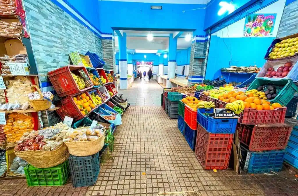 View of fruits and veggies for sale inside of a food market with blue walls in Chefchaouen.