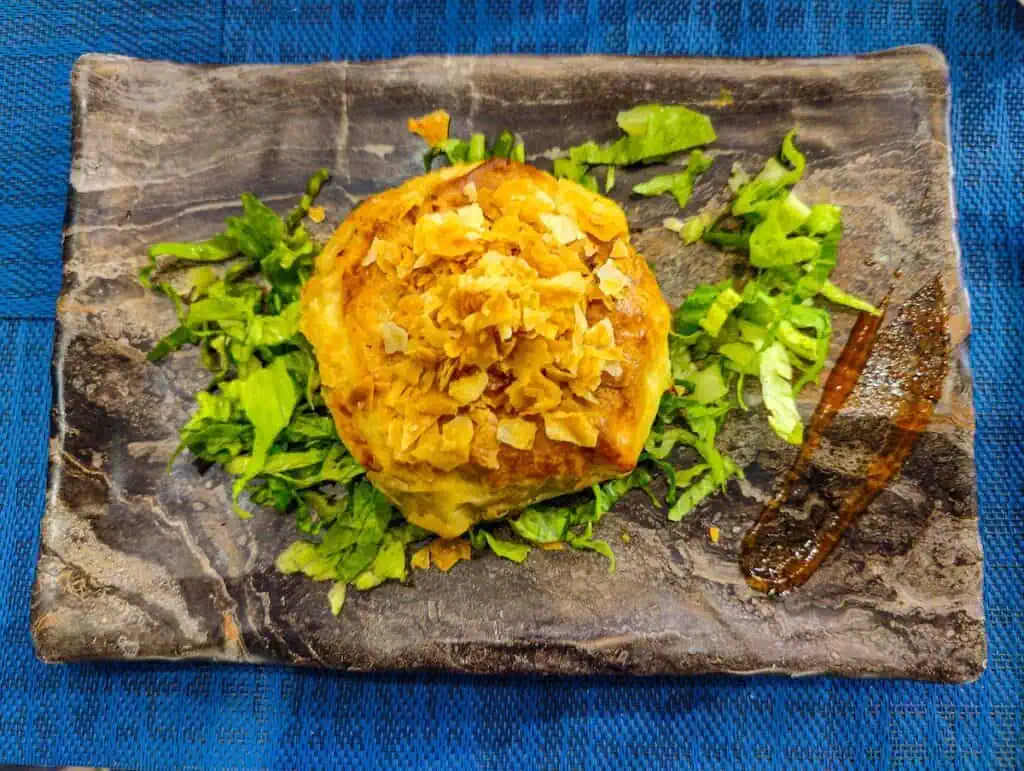 Aerial view of a round veggie bastilla on a slab of gray rock with lettuce all around it at one of the best restaurants in Tangier.
