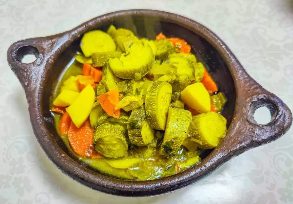 Aerial view of a vegetable tajine in a cast iron skillet with squash and carrots and potatoes.